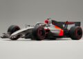 A silver and black Audi R26 concept Formula 1 race car featuring red accents, Pirelli tires, and Audi branding, shown on a plain gray background—ready for its Formula 1 debut in Melbourne.