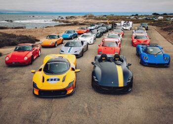 A group of high-performance sports cars, including Ferraris, Pagani, and Porsche models, line a coastal road—an impressive scene as the U.S. luxury automotive market is set to surpass $200 billion by 2035, according to a comprehensive BCG study.