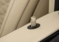 Close-up of a car door lock pin with a textured metallic finish and a "B" emblem, set in a beige leather door panel—echoing the luxury found as Brabus debuts the 800 Cabrio and XL 800 Cabrio.