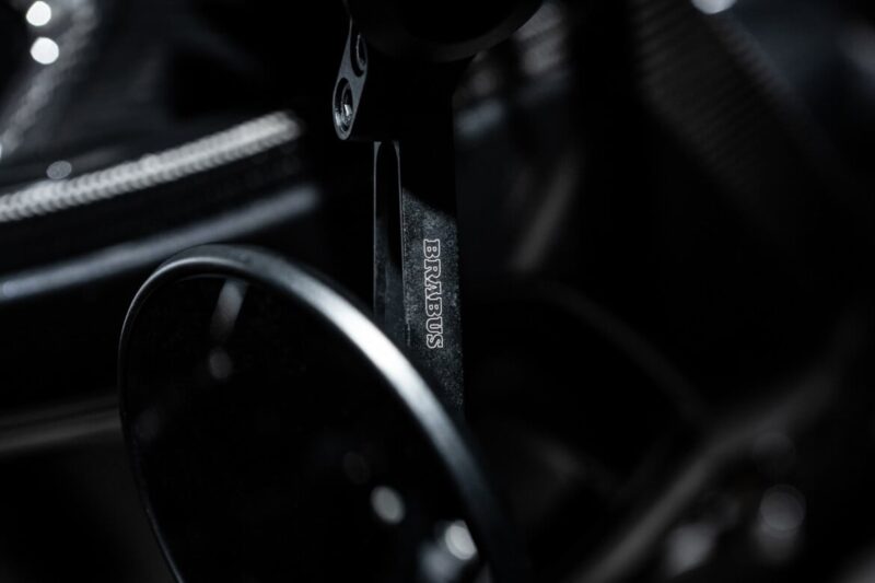 Close-up of a Brabus-branded paddle shifter in a car, with dark, out-of-focus background highlighting metallic and carbon fiber textures—an exclusive detail from the 2026 BRABUS Signature Edition.