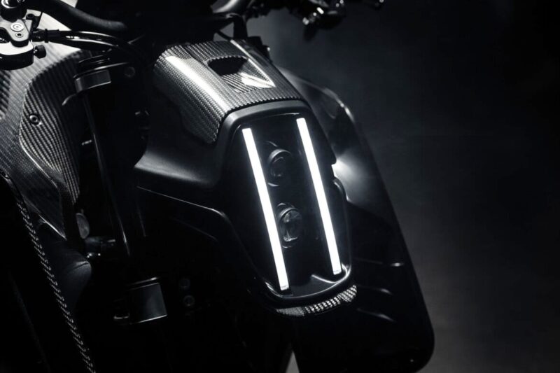 Close-up of the Signature Edition BRABUS 1400 R motorcycle's front headlight assembly, featuring two vertical LED light strips and a carbon fiber finish.