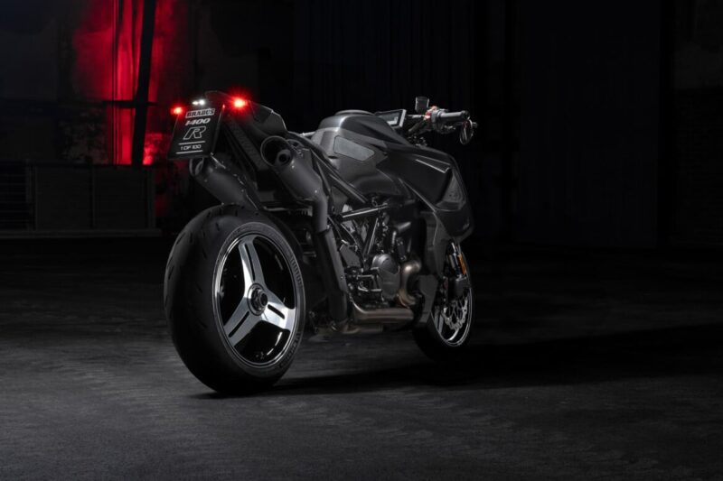 A black Signature Edition BRABUS 1400 R sport motorcycle with illuminated rear lights is parked indoors on a dark concrete floor, photographed from the back left side.