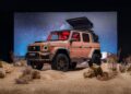 A tan Brabus-modified Mercedes-Benz G-Class SUV with a rooftop tent is parked on sandy terrain under a starry night sky, echoing the rugged spirit behind Brabus Debuts 800 Cabrio and XL 800 Cabrio.
