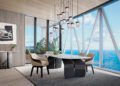 Modern conference room with a marble table, six chairs, pendant lights, large windows revealing an ocean view—echoing the luxury of Miami penthouses in Bentley Residences—with a plant and car artwork on the wall.