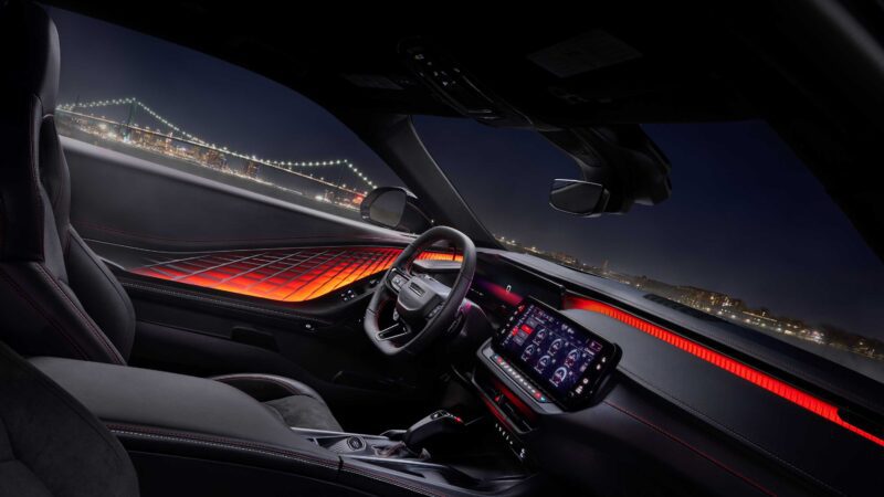 Car interior with illuminated red accent lighting, digital dashboard display, and steering wheel—this powerful sedan lets you take in city bridge views at night, offering premium features found in the best sedan options under $60,000.