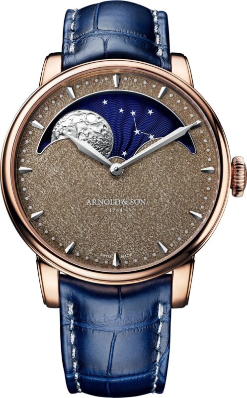 A luxury wristwatch with a blue leather strap, gold case, textured brown dial, moonphase display, and silver hands; the "ARNOLD & SON" logo on the face—an exquisite choice among the best luxury watches.