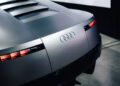 Close-up of the rear end of a silver Audi Concept C, showing the Audi logo and distinctive horizontal LED tail lights against an urban London backdrop.