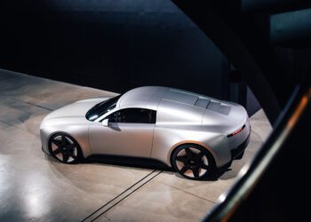 A sleek silver Audi Concept C with a futuristic design is parked indoors on a concrete floor in London, viewed from an elevated angle.