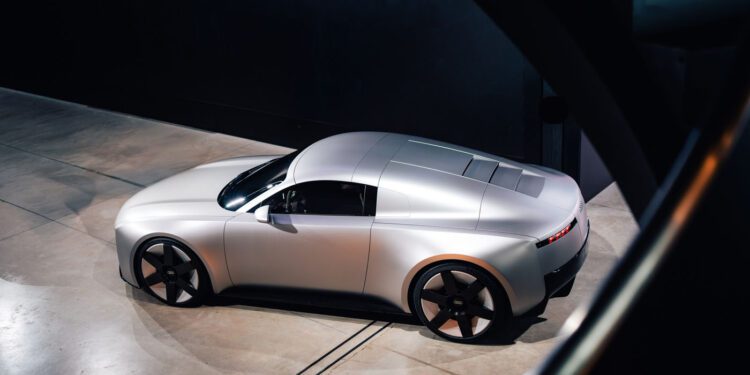 A sleek silver Audi Concept C with a futuristic design is parked indoors on a concrete floor in London, viewed from an elevated angle.