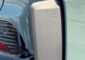 Close-up of a concealed rear spoiler mechanism labeled "Porsche Active Aero" on a light blue vehicle. Feature Exclusive: 2025 Icons of Porsche Dubai.