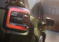 Close-up of a 2026 Jeep Recon’s rear taillight illuminated in daylight, with part of the all-electric Jeep's body and a blurred building in the background.