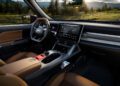 Interior view of the trail-ready, all-electric 2026 Jeep Recon featuring brown leather seats, a touchscreen display, digital controls, and a scenic forest landscape visible through the windows.