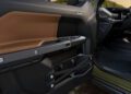 Close-up view of the interior driver-side door panel of a trail-ready Jeep, featuring brown and black materials, control buttons, and visible stitching.