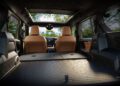 View from the open cargo area of the Trail-Ready 2026 Jeep Recon, with rear seats folded flat, showing a spacious interior with brown seats and a cityscape visible through the windshield.