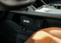 A black pouch with the Jeep logo is stored in a compartment under the dashboard of a Trail-Ready Jeep with brown leather seats.