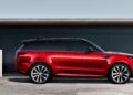 A red SUV, the 2025 Land Rover Range Rover Sport Dynamic SE PHEV, is parked next to an electric vehicle charging station on a concrete surface, with a modern building in the background.