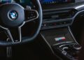 Close-up of the 2026 BMW M340i xDrive interior showing the steering wheel, digital display, gear selector, climate controls, and a "50 Jahre Edition" badge on the center console.