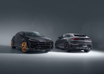 Two Lamborghini Urus SUVs are displayed in a studio; one faces front with gold wheels, the other shows the rear view with black wheels.