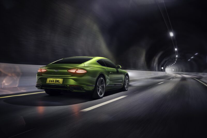 A green car, reminiscent of the 2026 Bentley Continental GT Speed, drives through a well-lit tunnel on a smooth, empty road.