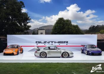 Three sports cars are displayed outdoors on a white platform in front of a "Gunther Werks" backdrop under partly cloudy skies, highlighting the latest from Gunther Werks dealers in the U.S. and Earth MotorCars.