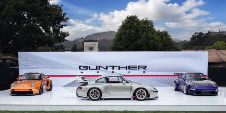 Three sports cars are displayed outdoors on a white platform in front of a "Gunther Werks" backdrop under partly cloudy skies, highlighting the latest from Gunther Werks dealers in the U.S. and Earth MotorCars.