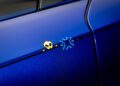 Close-up of a blue car door featuring a pixel art decal of a skull and blue pixel burst along the panel line.