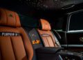 The image shows the backseat of a Rolls-Royce Black Badge Ghost with brown leather seats labeled "Player 3" and "Player 4," perfect for any gamer, and a starry light pattern on the ceiling.