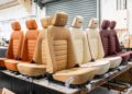 A row of luxury car seats in various colors is displayed in a workshop, with some seats featuring quilted patterns and Bentley logos on the headrests—a fitting tribute to the craftsmanship seen in limited editions like the Morgan Plus Four 75th Anniversary in the US.