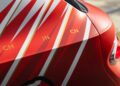 Close-up of a red car from the Bentley Honors Wartime Heroes Czech Squadron Collection, featuring white and gold angled stripes and the letters "CH," "JN," and "CN" in gold on the rear quarter panel.