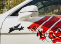 Close-up of a white car door featuring a side mirror, red and black poppy-themed graphics, diagonal stripes, and partial letters "EP" and "IS," highlighting Bentley Honors Wartime Heroes with the Czech Squadron Collection.
