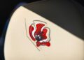 Close-up of a car seat with beige upholstery featuring an embroidered red and black flower design, inspired by Bentley Honors Wartime Heroes with the Czech Squadron Collection and 2025 Remembrance Car.