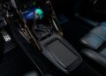 A close-up of a car's center console features a gear shift, illuminated controls, and metallic pedals—evoking the craftsmanship seen when Ringbrothers unveils their 800-plus horsepower 1969 Ford Mustang Mach 1 'KINGPIN' at the 2025 SEMA.