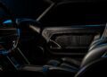 Interior view of a car showing the passenger seat, door panel, and part of the dashboard with dark, low-key lighting—evoking the bold style seen in Ringbrothers' 800-plus horsepower 1969 Ford Mustang Mach 1 'KINGPIN' unveiled at 2025 SEMA.