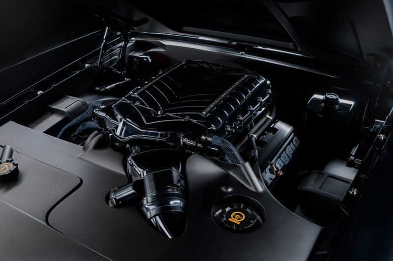 A close-up view of a clean, modern car engine with visible components and wiring under the hood, inspired by the power seen in Ringbrothers Unveils 800-Plus Horsepower 1969 Ford Mustang Mach 1 'KINGPIN' at 2025 SEMA.