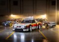 Three modified race cars, including the Subaru Brataroo, with decals and sponsor logos are parked indoors in a well-lit garage with a dark background, showcasing their Gymkhana-ready style for SEMA 2025.