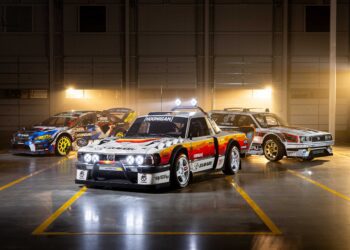Three modified race cars, including the Subaru Brataroo, with decals and sponsor logos are parked indoors in a well-lit garage with a dark background, showcasing their Gymkhana-ready style for SEMA 2025.