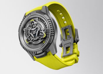 A modern collaboration watch, the URWERK x Ulysse Nardin UR-FREAK features a gray case, visible mechanical inner workings, and a textured bright yellow strap, displayed against a plain light gray background.