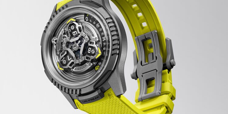 A modern collaboration watch, the URWERK x Ulysse Nardin UR-FREAK features a gray case, visible mechanical inner workings, and a textured bright yellow strap, displayed against a plain light gray background.