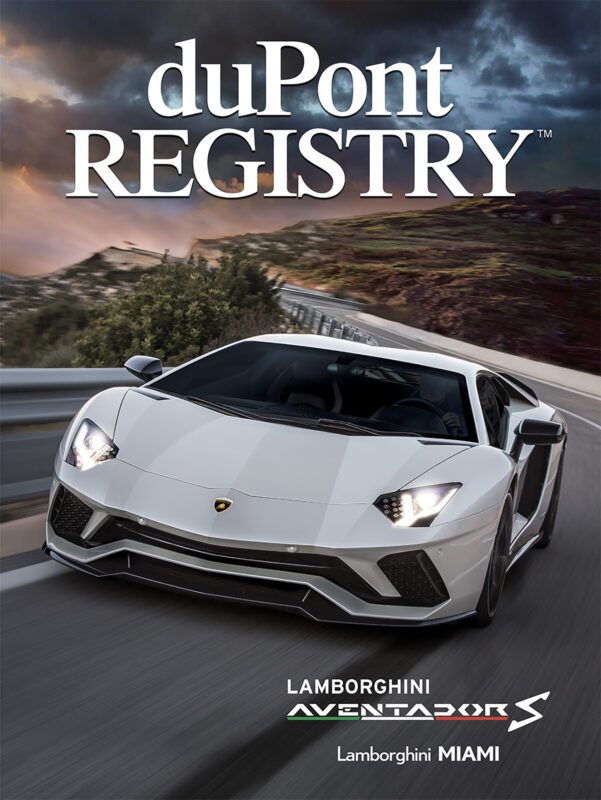 A white Lamborghini Aventador S cruises along a winding mountain road, gracing the cover of duPont REGISTRY magazine’s special 40th Anniversary Cover Cars issue.