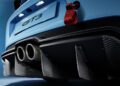 Close-up of the rear of a blue sports car labeled GT3, showing dual exhaust pipes, a carbon fiber diffuser, and a red tow strap.