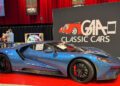 A blue Ford GT sports car is displayed indoors at a classic car show, parked in front of a sign that reads "GAA Classic Cars.