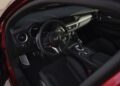 Interior view of a modern Alfa Romeo showing the steering wheel, dashboard, center console with controls, and black suede seats—evoking the style and performance of the Giulia Quadrifoglio.