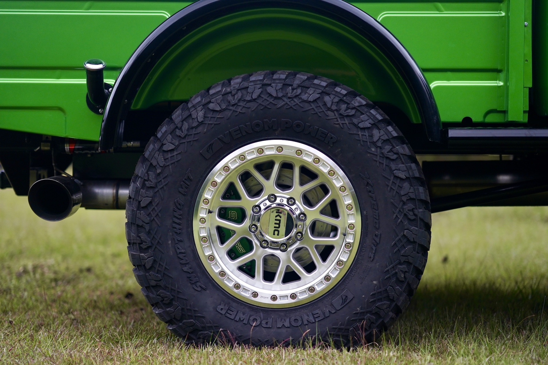 Close-up of a rugged off-road tire and silver alloy wheel on a green Dodge Power Wagon Crew Cab, parked on grass.