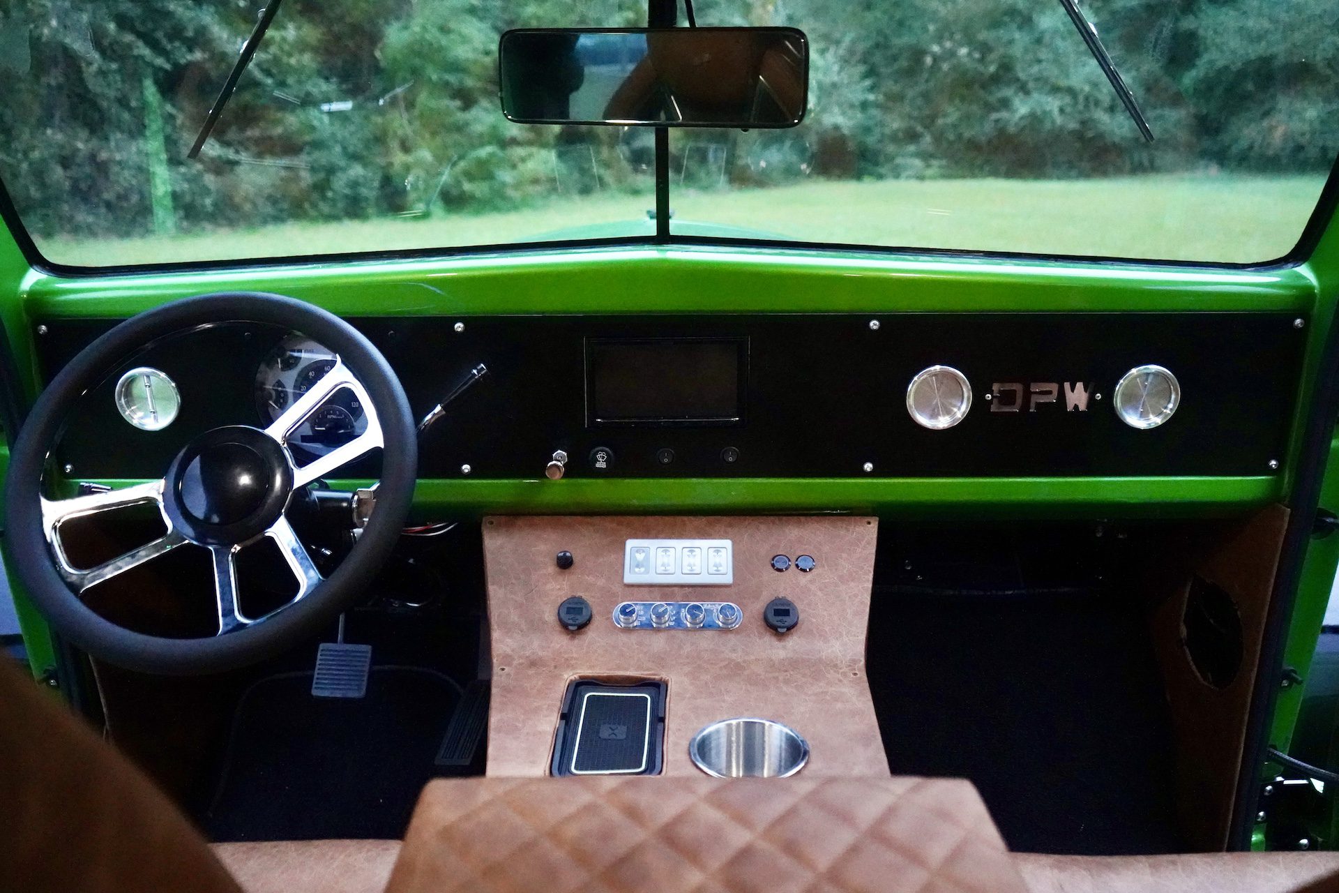 The interior of a green Dodge Power Wagon Crew Cab features a black and chrome steering wheel, minimalist dashboard, and brown leather-covered center console with controls and cupholder—now available for sale.