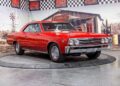 A red 1967 Chevrolet Chevelle SS coupe, a true icon among Classic Muscle Cars, is displayed on a rotating platform in an indoor showroom with vintage decor.