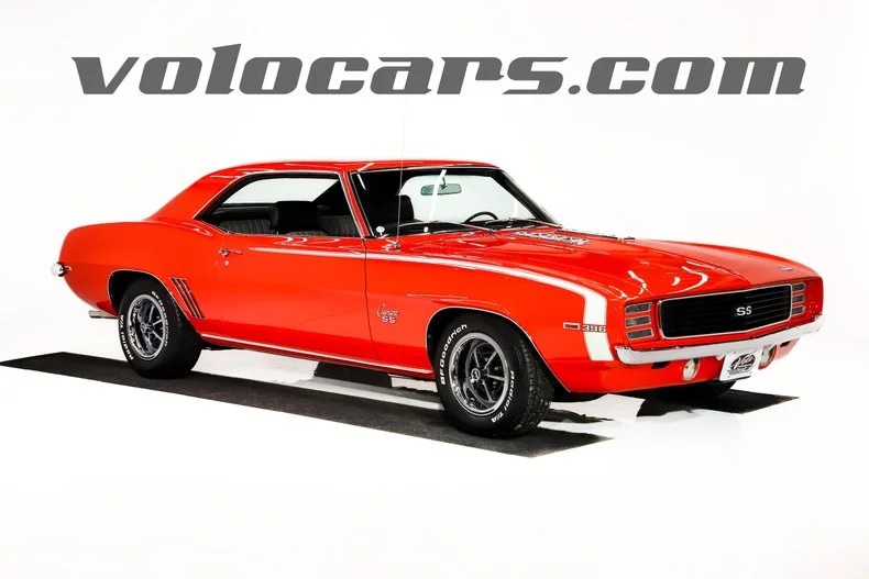 A red 1969 Chevrolet Camaro SS coupe, a true icon among classic muscle cars, is displayed in a studio with a white background and "volocars.com" text above the car.
