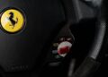 Close-up of a Ferrari steering wheel showing the logo, airbag label, and drive mode selector—offering a glimpse of Your Chance To Own The Final Ferrari That Michael Schumacher Helped Develop.