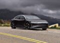 A dark gray luxury sedan, the 2026 Lucid Air Touring, parked roadside with mountains and cloudy skies in the background. Review: 2026 Lucid Air Touring hits the EV sweet spot in both style and performance.