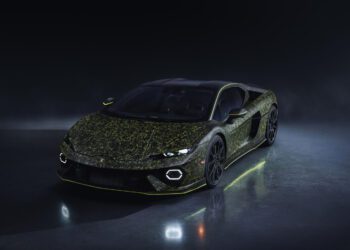 A Lamborghini sports car with a dark, speckled green and black exterior finish, photographed on a glossy surface under low lighting.