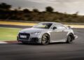 A silver Audi TT sports car, celebrating the 50th anniversary of the iconic Audi five-cylinder engine, drives around a racetrack corner, with a blurred background indicating motion.